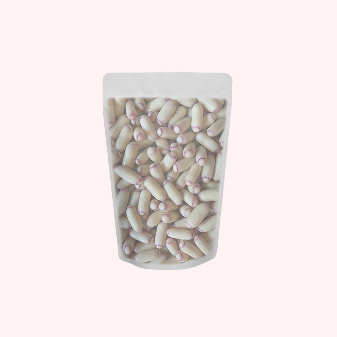 Clear pouch filled with white chocolate bullet candies featuring creamy white coating and pink center filling
