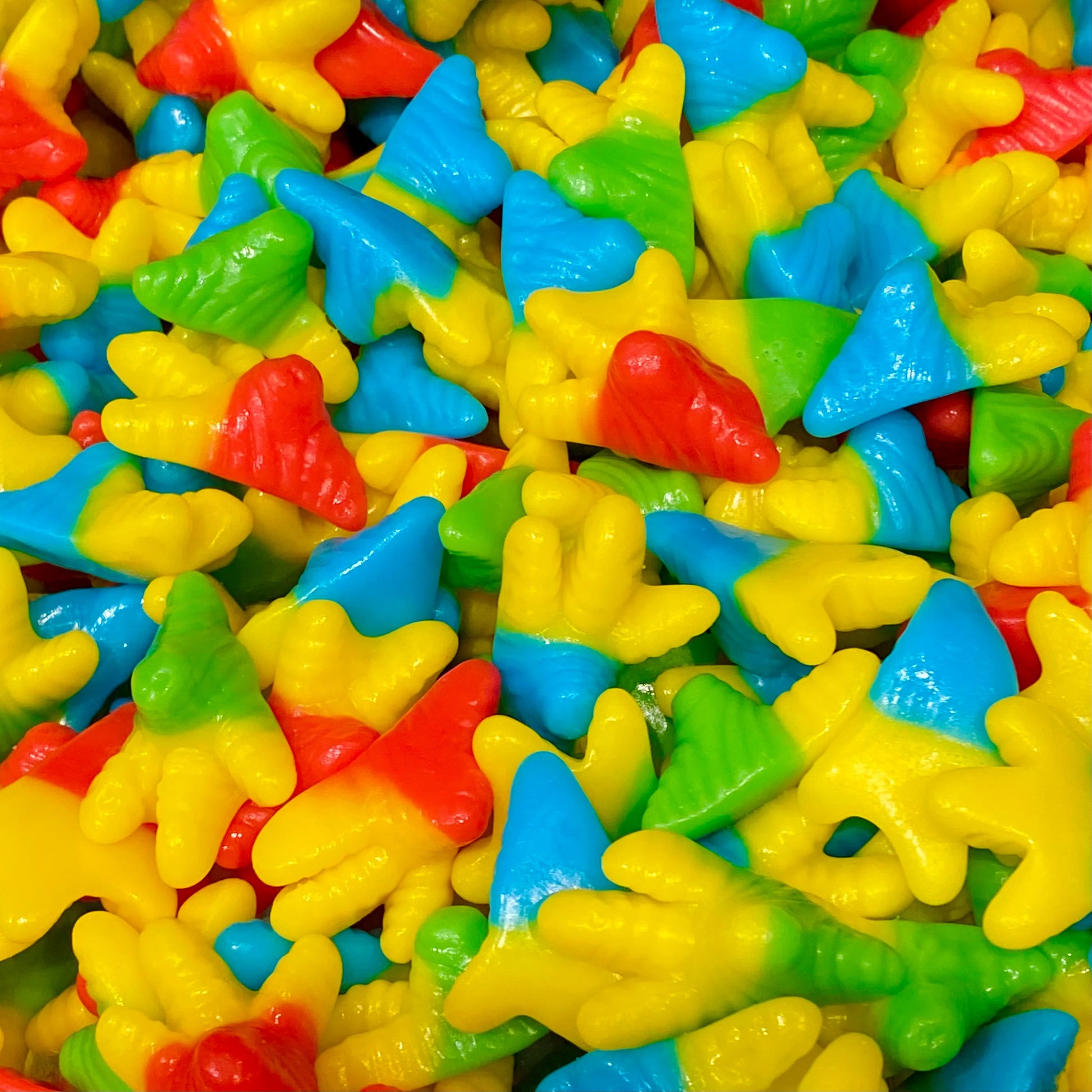 Colorful chicken feet-shaped gummy candies in bright yellow, blue, green, and red colors with detailed foot and claw designs scattered across the frame