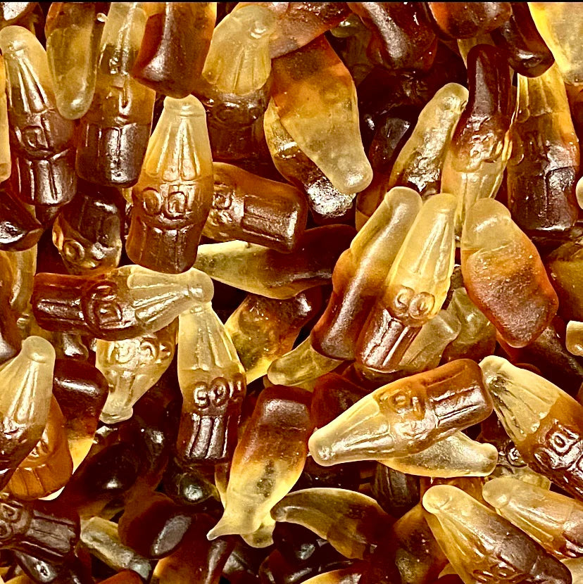Brown and amber cola bottle-shaped gummy candies with detailed bottle designs and embossed text, showing classic soda bottle shapes in various shades of cola colors