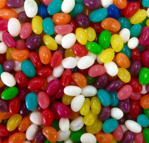 Colorful mini jellybeans in assorted flavors including red, orange, yellow, green, blue, purple, white, and pink scattered across the frame showing their small oval bean shapes