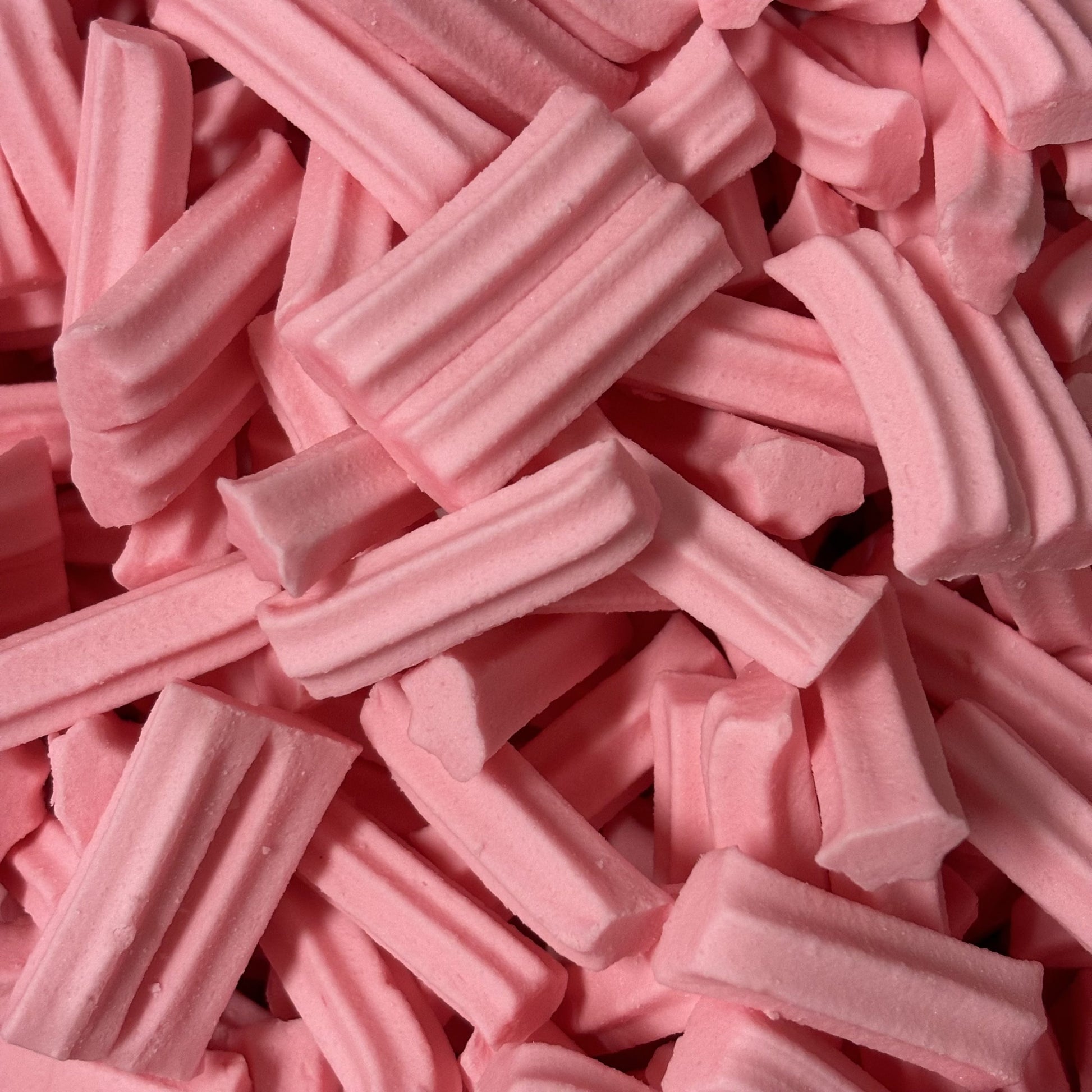 Pink mini musk sticks candy with ridged cylindrical shapes and traditional musk flavor, showing classic Australian confectionery in bite-sized form