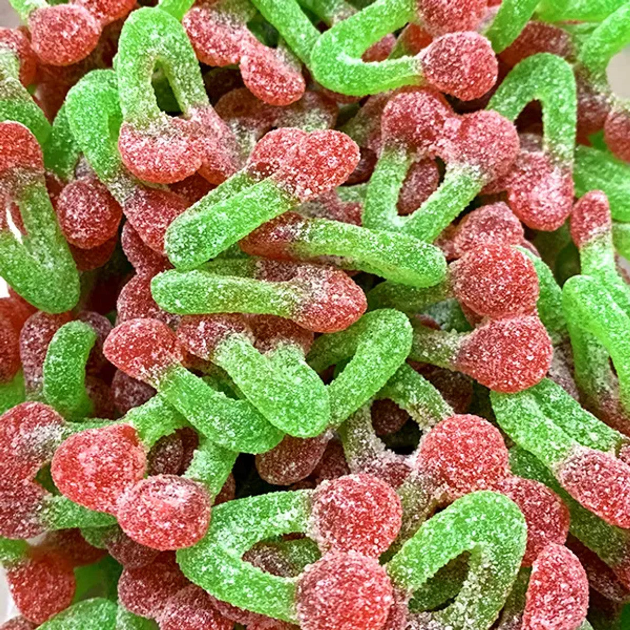 Sour cherry bomb gummy candies in red and green colors covered in sugar crystals, showing ring and curved shapes with tangy coating