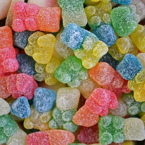 Colorful sour gummy bears in assorted flavors including red, blue, green, yellow, orange, and clear, covered in sugar crystals showing classic bear shapes