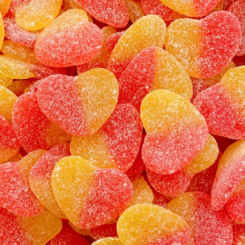 Heart-shaped sour peach gummy candies in orange and red colors covered in sugar crystals, showing romantic heart shapes with tangy peach flavoring